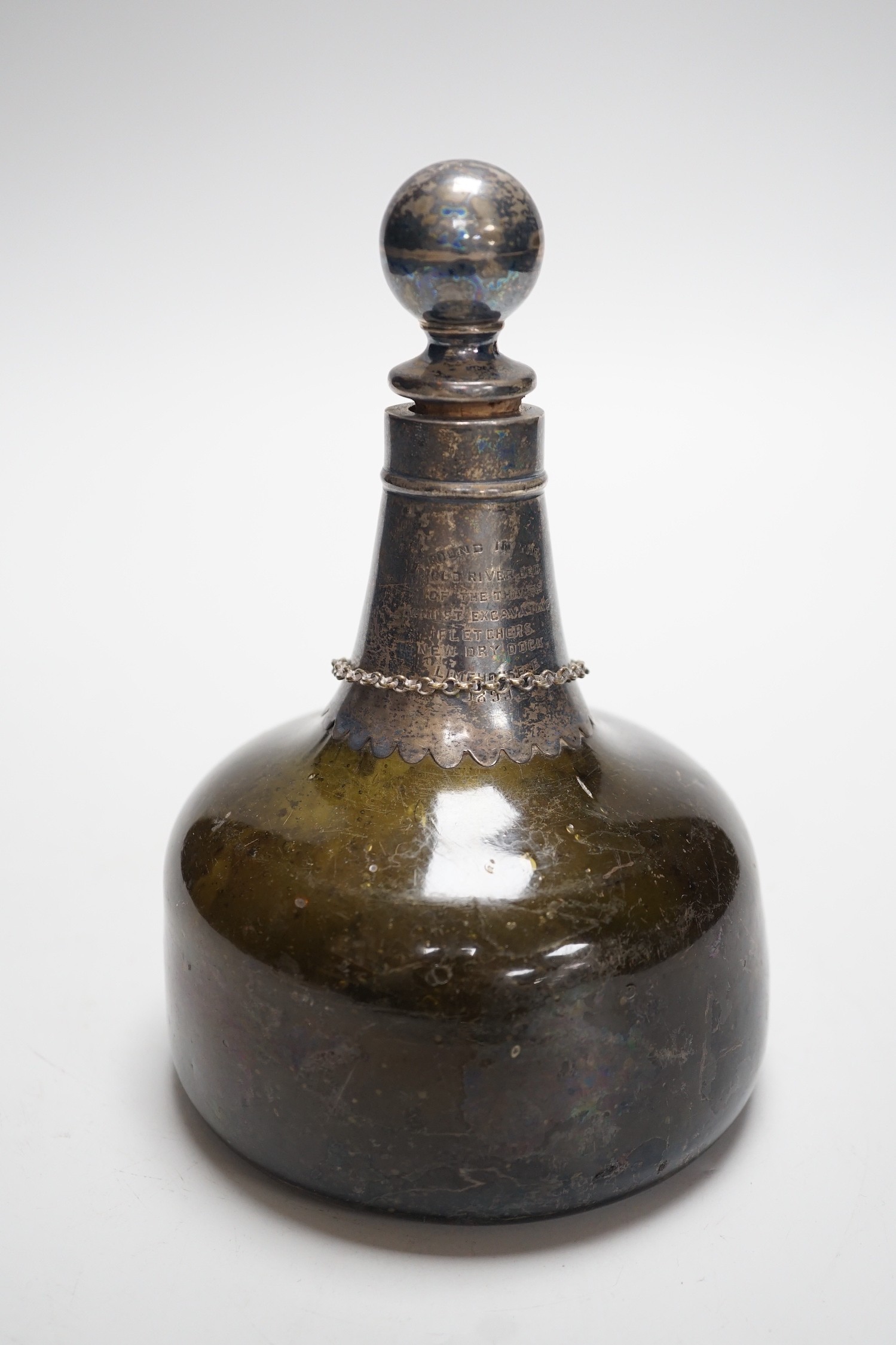 An 18th century green glass onion-shape bottle, with later silver mount, London, 1899, together with a George III silver 'S' decanter label, Phipps & Robinson, London, 1806. 17cm